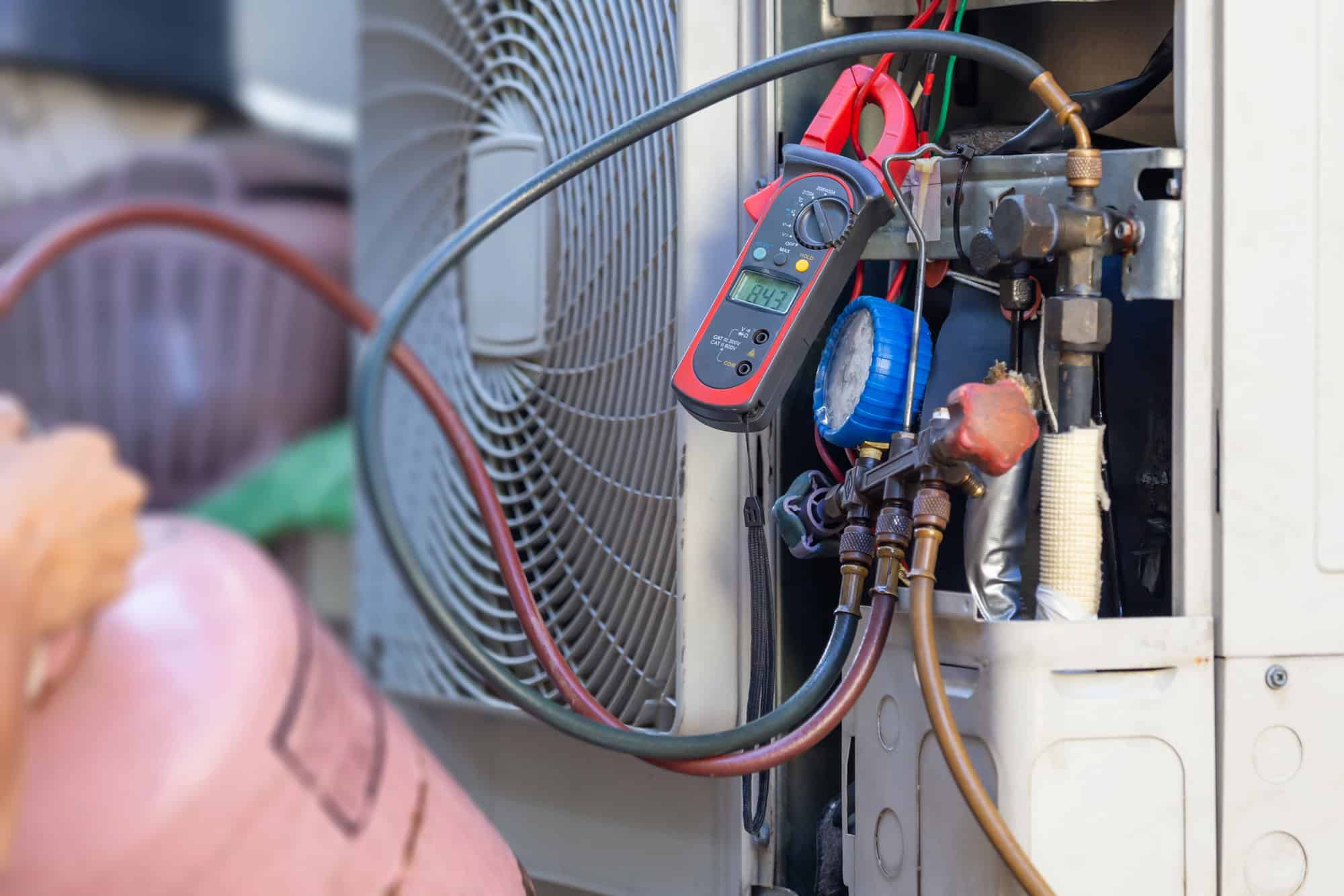 Technician checking AC refrigerant levels with gauges